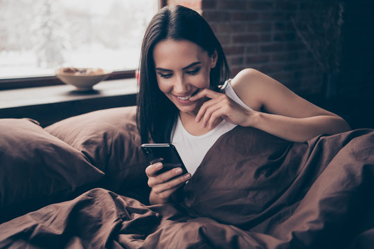 Close-up portrait of her she nice-looking attractive lovely charming flirty coquettish cheerful girl lying in bed chatting using app 5g industrial brick loft style interior room flat apartment house