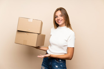 Young blonde woman over isolated background holding a box to move it to another site