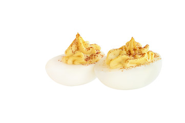 Two deviled egg halves sprinkled with paprika and isolated over a white background. Clipping path...