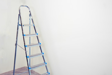 Big metal ladder on the white background of the wall, copy space