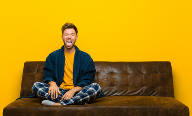 young man wearing pajamas with cheerful, carefree, rebellious attitude, joking and sticking tongue...