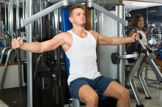 Young man using fly machine in gym.