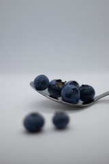 Some fresh and healthy blueberries on top of a spoon with white background