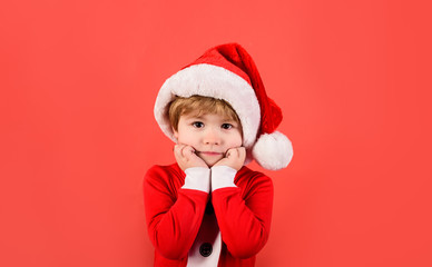 Merry christmas. Christmas time. Santa helper. Happy New Year. Christmas kid in red hat. New Year's holiday. Surprised boy in Santa costume. Little boy in Santa Claus hat. Little kid in Santa costume.