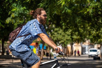 Hipster looking guy riding his bicycle on Parc de Ses Estacions in Palma de Mallorca Spain.