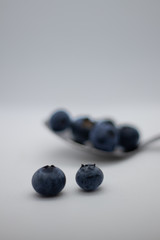 Some fresh and healthy blueberries on top of a spoon with white background