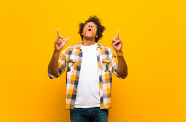 young black man feeling awed and open mouthed pointing upwards with a shocked and surprised look...