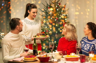 holidays and celebration concept - happy friends having christmas dinner at home