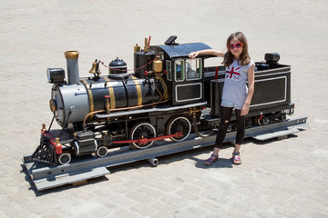 Kleines Mädchen vor kleiner Lokomotive und Waggon 