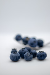 Some fresh and healthy blueberries on top of a spoon with white background