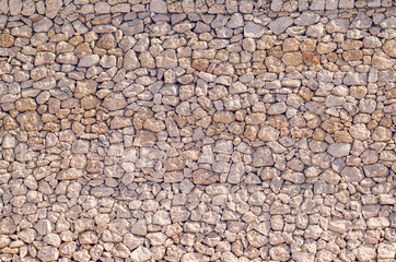 Old beige stone wall background texture close up