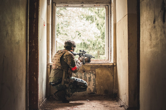 Airsoft sniper aiming out of the window