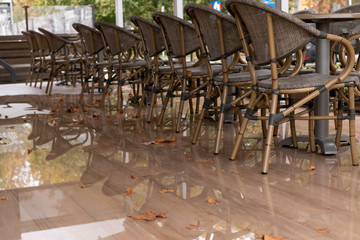 Autumn story: a row of empty chairs on the terrace of a street c