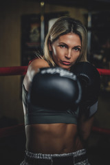 Attractive female boxer is making her strong punch while posing for photographer.