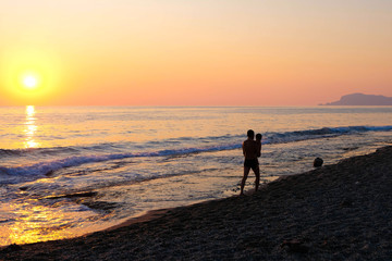Father and sun walking on beach at sunset