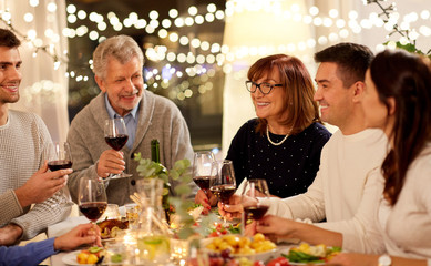 celebration, holidays and people concept - happy family having dinner party, drinking red wine and toasting at home