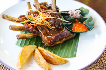Roasted pork ribs with potato with sauce in white plate. Indonesia style roasted pork ribs. Food concept. 