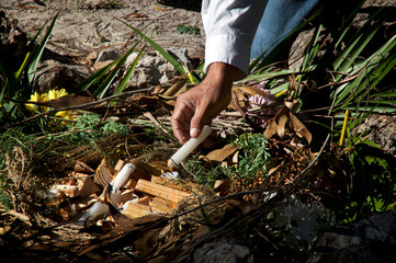 Obraz premium A mayan priest is lighting fire with candles in ceremonial fire ritual, flowers and herbs can be seen.
