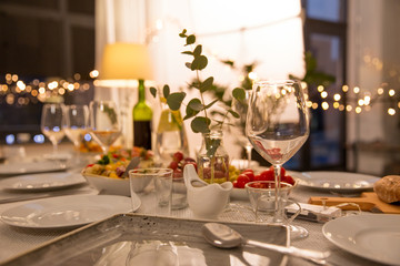 celebration, holidays, catering and eating concept - table served with plates, wine glasses and...
