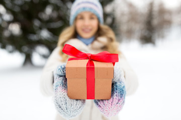 christmas, holidays and leisure concept - close up of happy young woman with gift box outdoors in winter