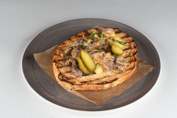 Ciabatta toast with fried button mushrooms, pork and pickled cucumbers isolated on white flat lay