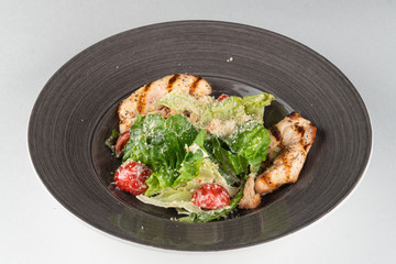 Classic caesar salad with grilled chicken fillet, greens and cherry tomatoes isolated on white background
