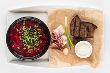 Top view of ukrainian borscht served with lard slices, rye toasts, green onion and garlic, isolated...