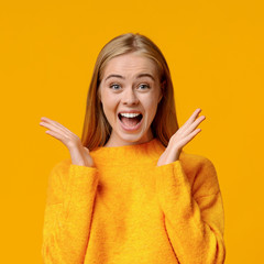 Portrait of amazed teenage girl over orange studio background