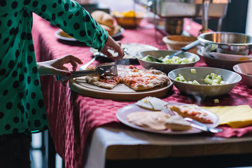 Buffet table with pizza on wooden tray