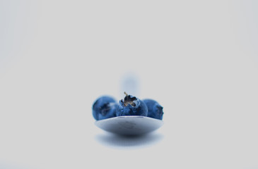 Some fresh and healthy blueberries on top of a spoon with white background