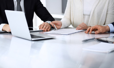 Business people discussing contract working together at meeting at the glass desk in modern office. Unknown businessman and woman with colleagues or lawyers at negotiation. Teamwork and partnership