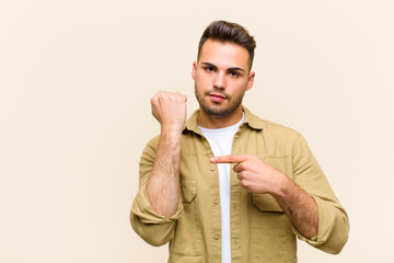 young hispanic man looking impatient and angry, pointing at watch, asking for punctuality, wants to...