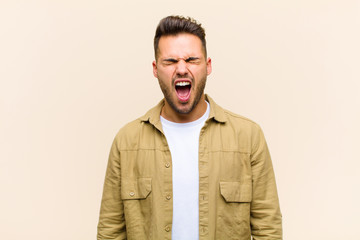 young hispanic man shouting aggressively, looking very angry, frustrated, outraged or annoyed,...