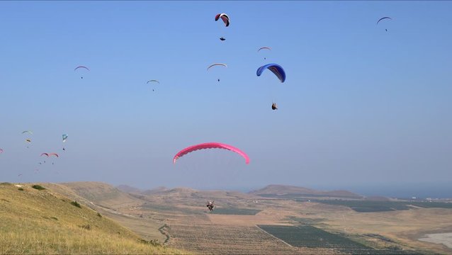 beautiful landscape with mountains, blue sky and flying paragliders over fields