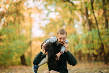 A mother and son play, have a fun and laugh in autumn forest.