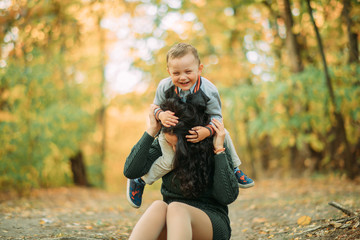 Naklejka na ściany i meble A mother and son play, have a fun and laugh in autumn forest.