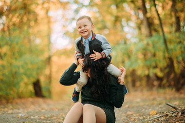 A mother and son play, have a fun and laugh in autumn forest.