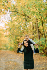 A mother and son play, have a fun and laugh in autumn forest.