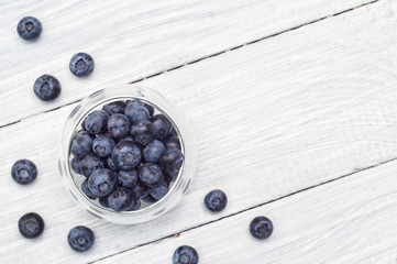 Blueberries in a glass plate on a white wooden table