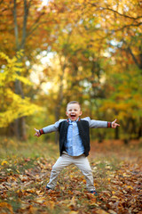 Rapturous and happy child boy stands in autumn forest.