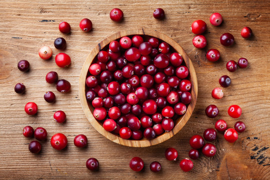 Ripe fresh cranberry in wooden bowl on rustic table top view.