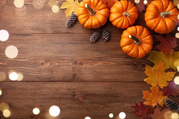 Fototapeta na wymiar Autumn Thanksgiving background. Pumpkins and leaves on wooden table top view.