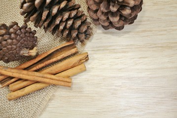 Cinnamon and pine cones on a sackcloth and plank background