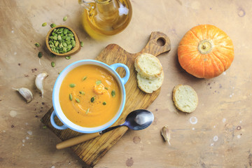 Pumpkin soup and organic pumpkins on rustic table.