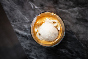 Affogato coffee: espresso shot with salted caramel icecream on classic marble table background, top view.
