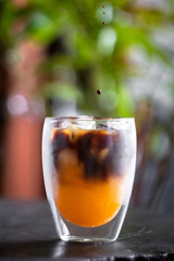 Iced fresh orange juice topped with espresso on wooden table in a garden; as sunrise coffee make a good day.