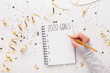 Woman writing down in notepad with 2020 goals