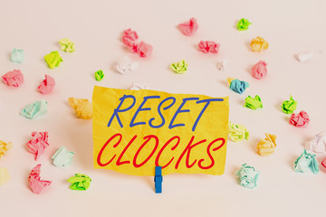 Word writing text Reset Clocks. Business photo showcasing To revisit return to or recreate a time or era from the past Colored crumpled papers empty reminder white floor background clothespin