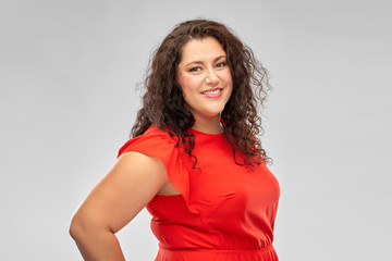 Fototapeta premium people and portrait concept - happy woman in red dress over grey background