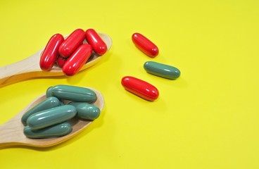 B vitamins and zinc capsules in a wooden spoon on a yellow background
